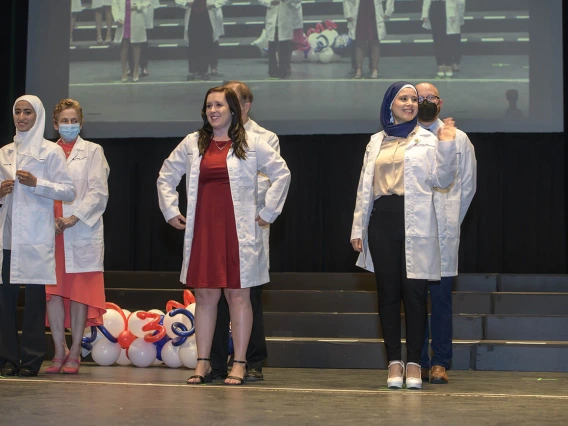 (Front row from left) Sarah Aloqili, Lauren Overholt and Zahraa Ahmed receive their white coats during the R. Ken Coit College of Pharmacy class of 2023 white coat ceremony.