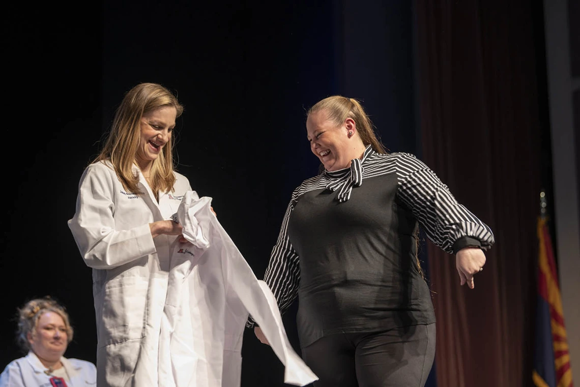 Professor Lindsay Bouchard presents Pamela Michel her coat at the UArizona College of Nursing white coat ceremony.