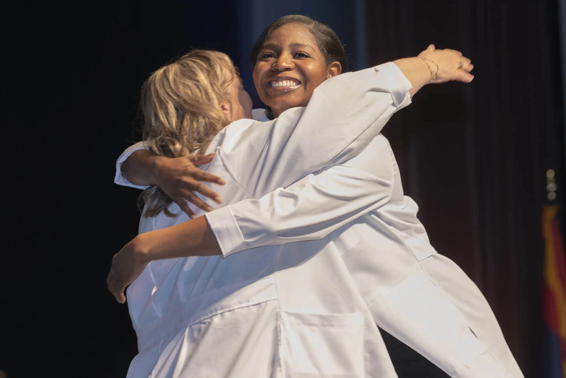 Professor Gloanna Peek hugs Nicole Robinson during the UArizona College of Nursing white coat ceremony.