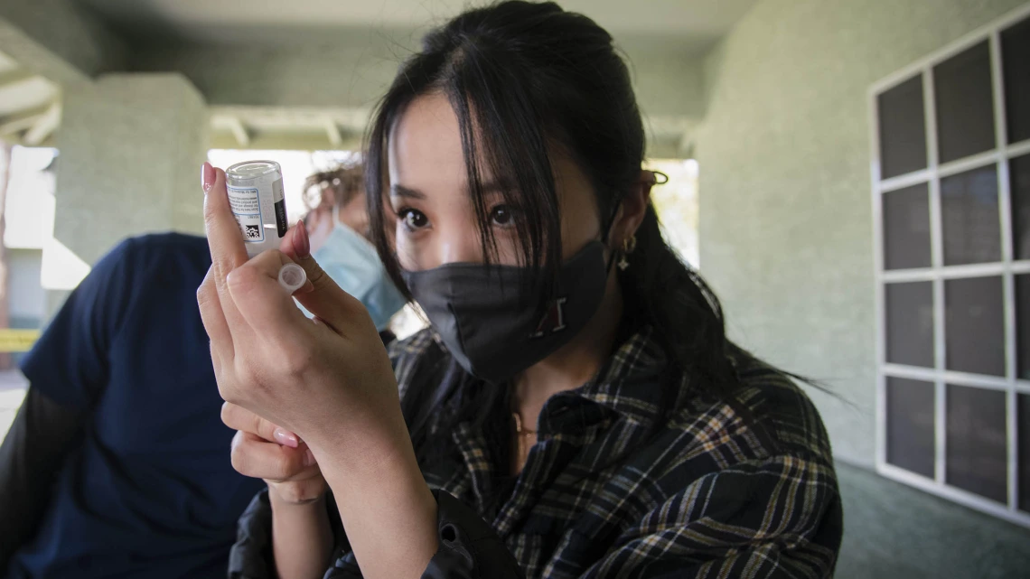 Second-year College of Pharmacy student Lisa Wan prepares to vaccinate a patient against the virus that causes COVID-19.