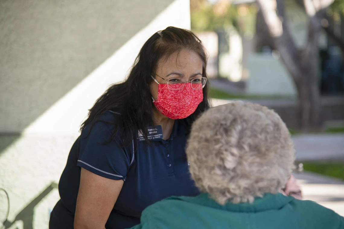 Nancy Alvarez, College of Pharmacy associate dean of academic and professional affairs for Phoenix, speaks with an elderly vaccine recipient from El Mirage Senior Village public housing complex. Patients stay under observation for 15 minutes after receiving the vaccine to make sure there are no adverse reactions.