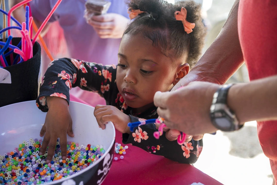 Ar'jianna Roberts grabs beads to put on the spider she made during the recent Family SciFest at Children's Museum Tucson.