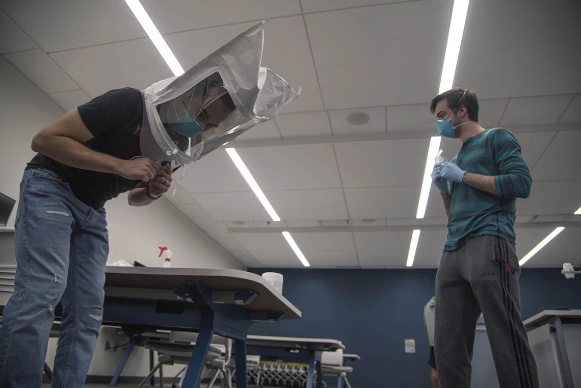 Under the watchful eye of student-volunteer Billy Evans, second-year College of Medicine – Tucson student Alexandre Cavalcante bends over while wearing a hood and his N95 mask. This is one of seven exercises the students must do during the mask-fit test. 