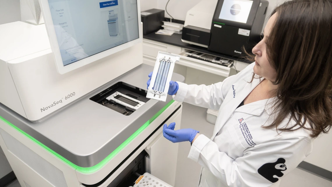 Anna Williams prepares to load a flow cell into the PANDA Core for Genome and Microbiome Research’s NovaSeq 6000 genome sequencer. The flow cell is what DNA samples are pumped into and what they bind to as they’re processed into sequenced reads. 