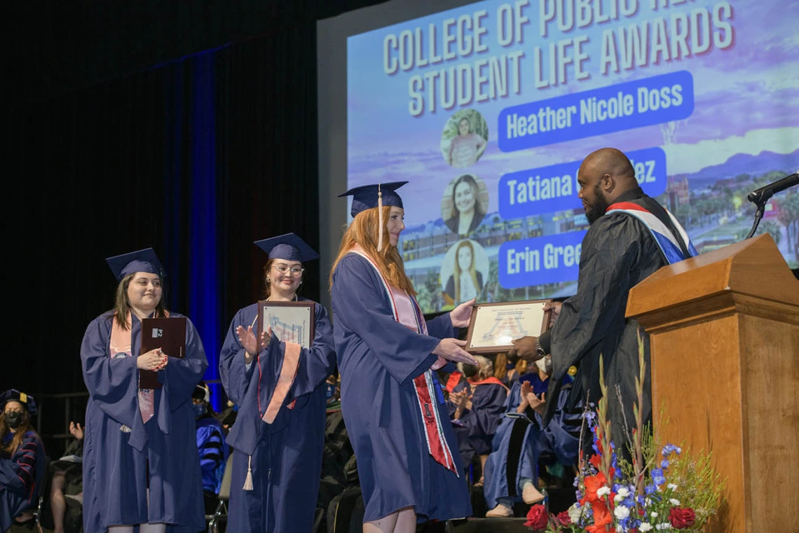 (From left) Heather Nicole Doss, MPH, Tatiana Gonzalez, MPH, and Erin Green receive Student Life Awards from Andre Dickerson, MA, MBA, assistant dean of student services and alumni affairs, during the 2022 Mel and Enid Zuckerman College of Public Health spring convocation.