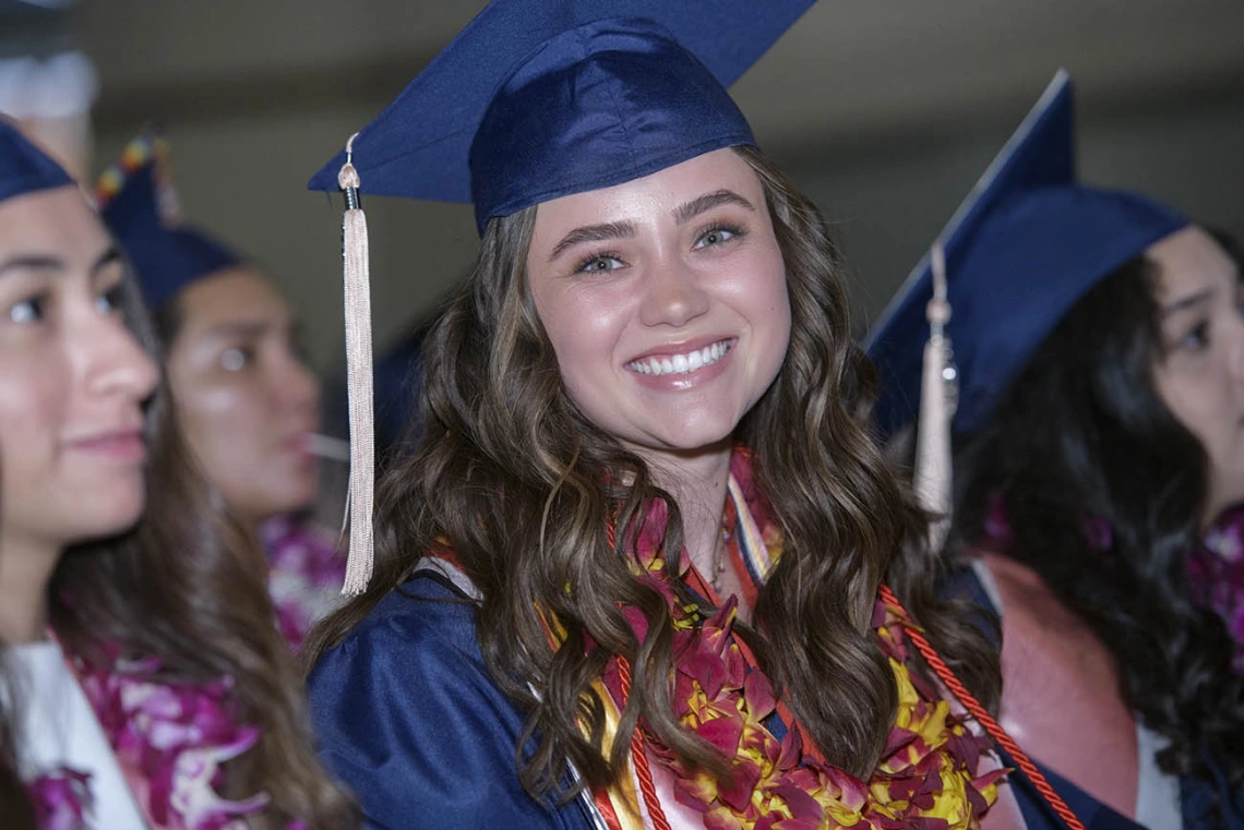 Edda Anderson wears a graduation lei with the traditional cap and gown as she waits to cross the Centennial Hall stage to receive a bachelor’s degree at the 2022 Mel and Enid Zuckerman College of Public Health spring convocation.