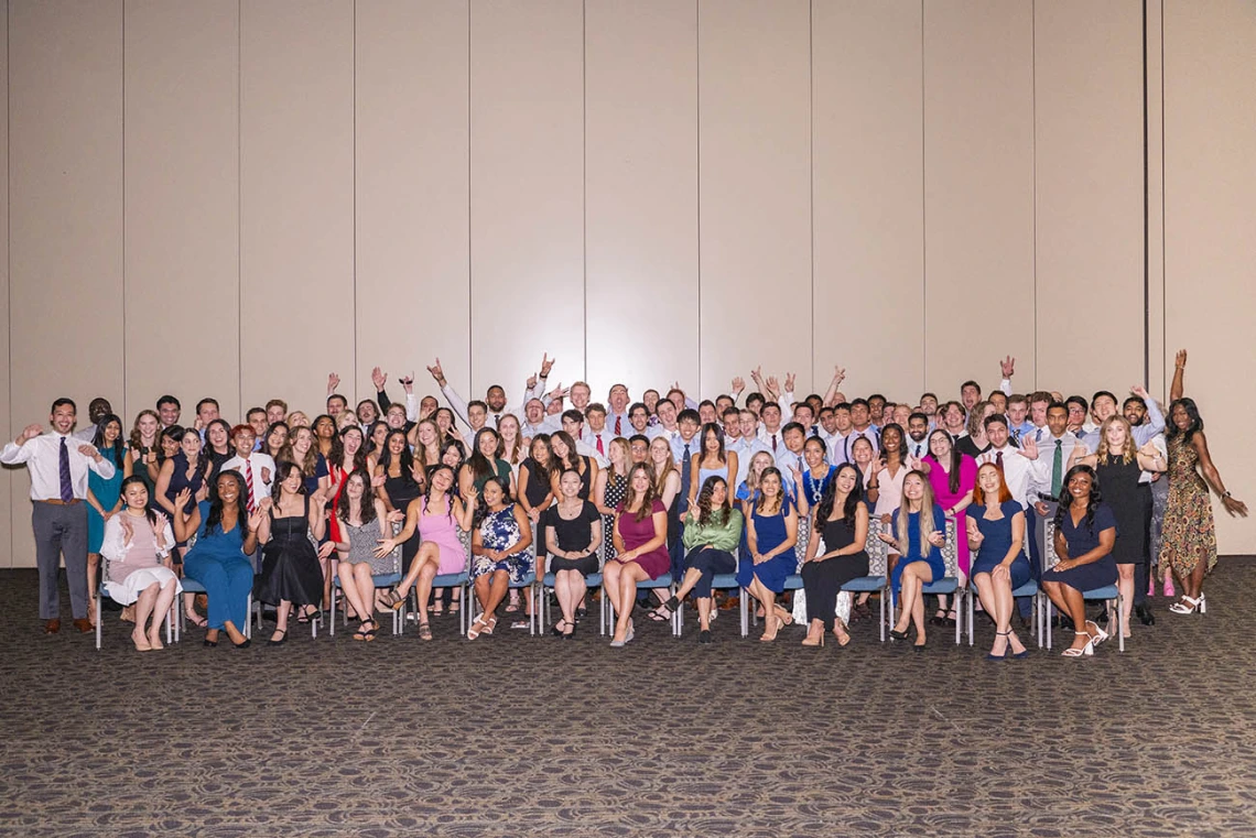 A group of 120 new medical students pose for a photo in large group sitting and standing. 