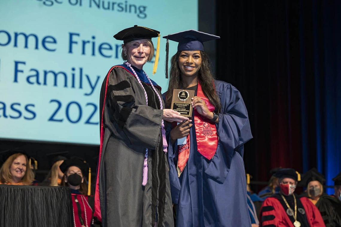 College of Nursing interim Dean Kathleen Insel, PhD, presents the Gladys E. Sorensen Award for Academic Excellence to Leila Darbouze, Master of Science in Nursing Entry to the Profession student, at the college’s 2022 summer commencement.