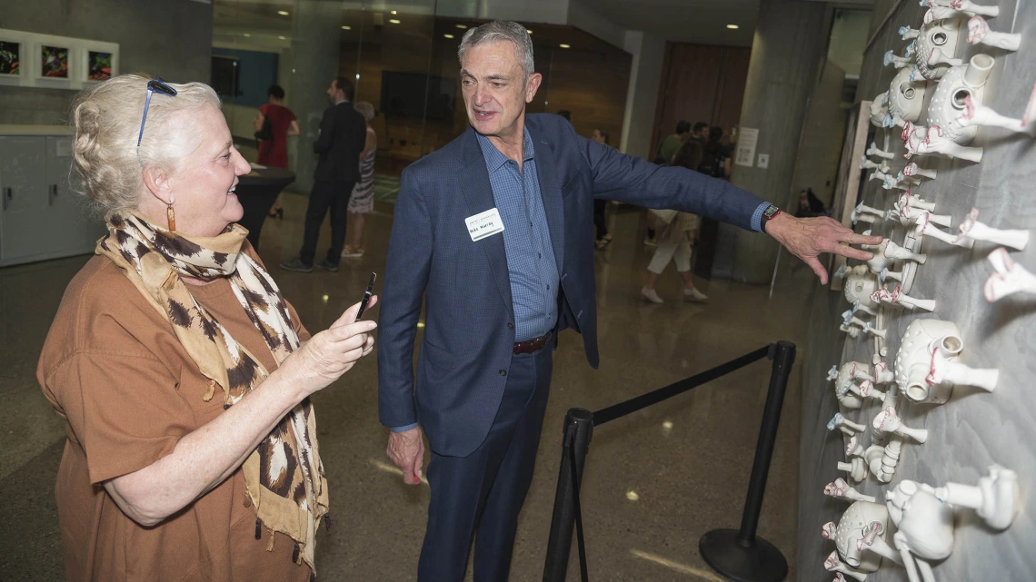 Michael Murray, MD, PhD, MCCM, a professor of anesthesiology and internal medicine in the College of Medicine – Phoenix, tells his wife, Cate Murray, about the ceramic piece artist Danielle Wood created based on his research during the public opening of the Artist + Researcher exhibition at the Health Sciences Education Building on the Phoenix Biosciences Core.