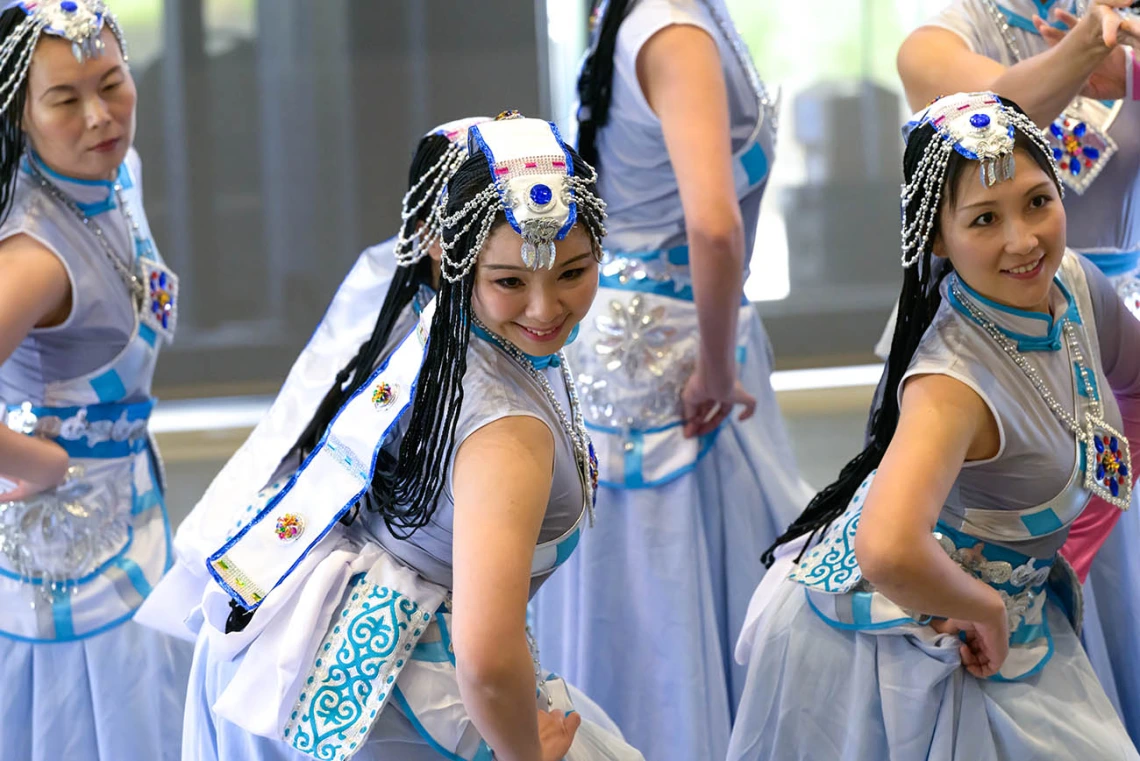 Three women wearing fancy traditional Chinese dance costumes perform a dance. 