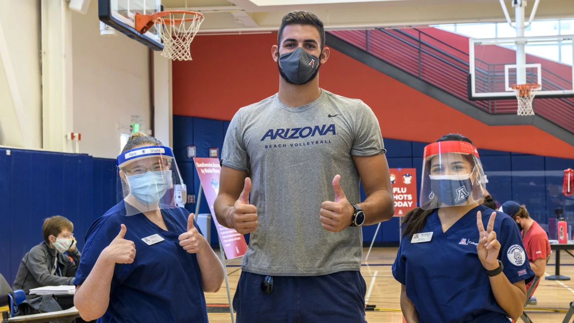 Chase Jones, who is in the University of Arizona men’s indoor volleyball club (center), poses with College of Nursing master’s degree students Hailey Finn (left) and Michelle Garcia (right) at the student-run flu shot clinic.