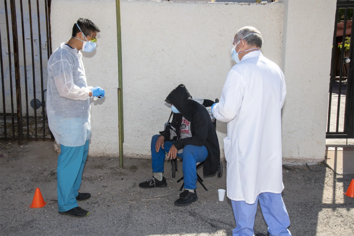 Christian Bergman (left) speaks with a person at Tucson’s Z Mansion downtown soup kitchen. Bergman and other medical students are helping provide health care services to this vulnerable population.