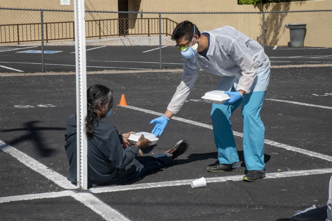 Medical student Christian Bergman offers food to a person at Z Mansion, a soup kitchen for homeless people several times a week.