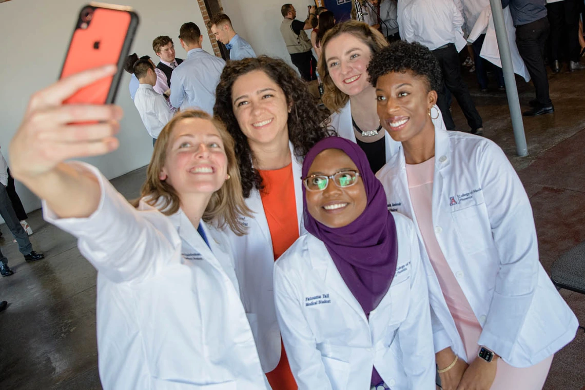 Rachel "R" Reichenbach, Theresa Riley, Fatouma Tall, Rose Graf and Shannon Alsobrooks take a group selfie while sporting their new white coats.