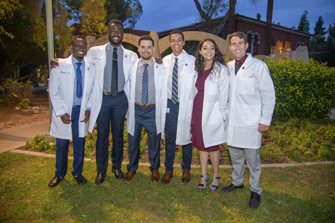 UArizona College of Medicine – Tucson classmates, from left, Toluwalase Talabi, Ayomide Odeneye, Ben Litmanovich, Sascha Delzepich, Aseel Ibrahim and Max Coffeen pose for a photo outside of Centennial Hall after receiving their white coats.