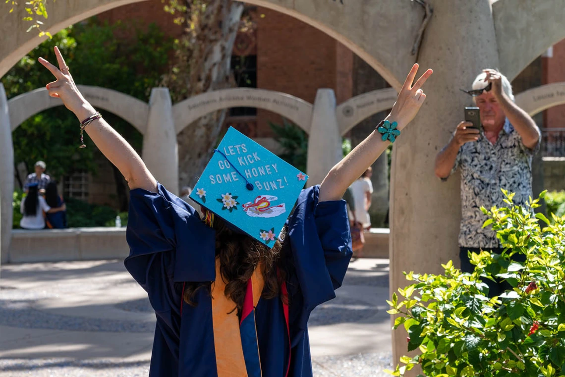 Hailey Sexton raises her arms victoriously after the College of Nursing graduation ceremony.