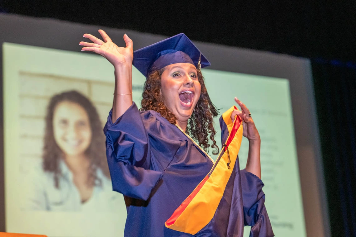 Asma Isack waves to the crowd during the College of Nursing’s August commencement at Centennial Hall.