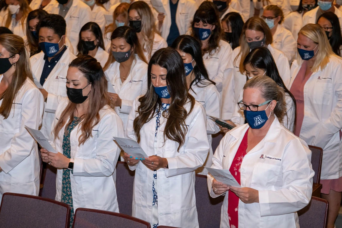 Doctor of Nursing Practice students recite the student oath of responsibility after they were each presented with their white coats. 