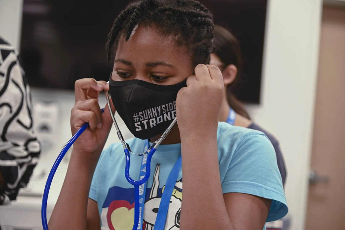 ACES camper Victoria Vigbedorh puts on a stethoscope so she can listen to the patient simulator’s heartbeat.