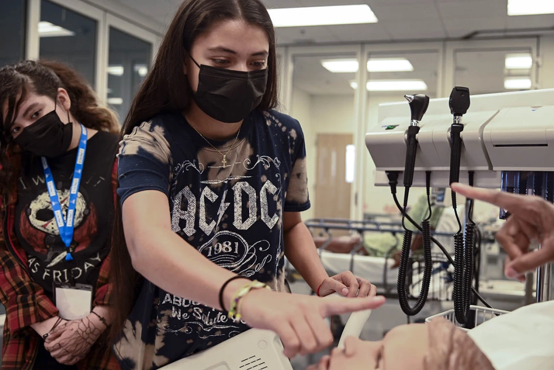 ACES camper Yazmin Pino moves her finger left to right to see if the patient simulator’s eyes will follow her movement.