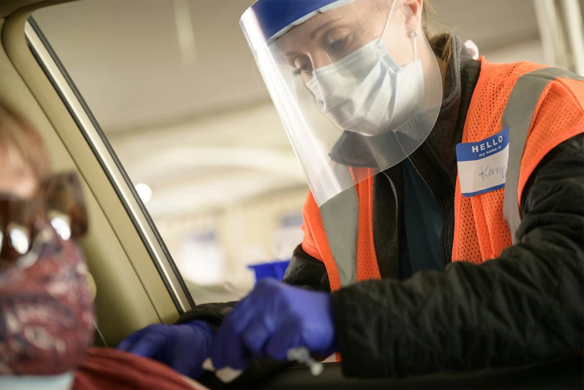 Kerry Johnson uses an alcohol swab to disinfect a driver’s arm at the site of injection.