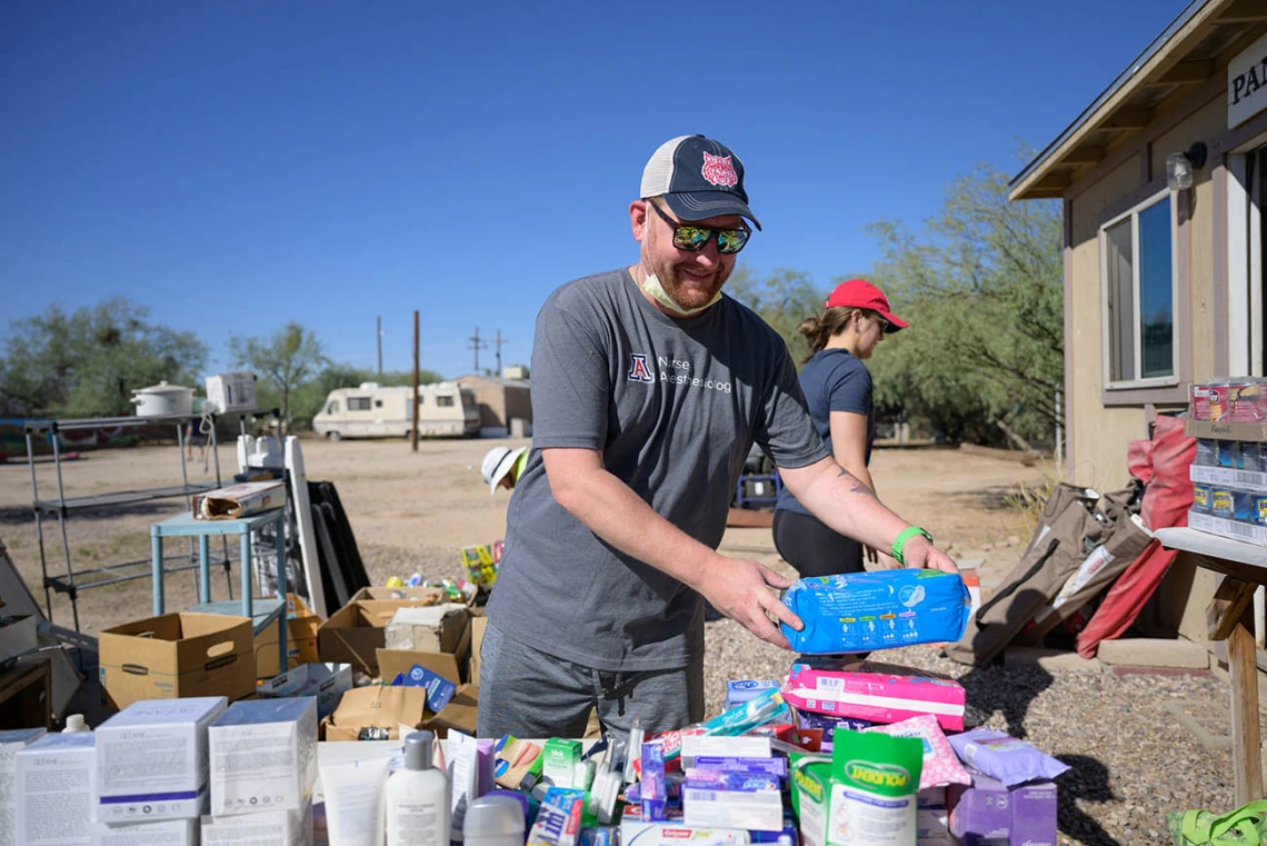 A man in a baseball hat stands outside a building as he sorts donated toiletrees.