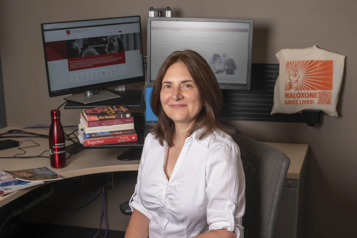 Bridget Murphy at her desk with computer monitors and books.