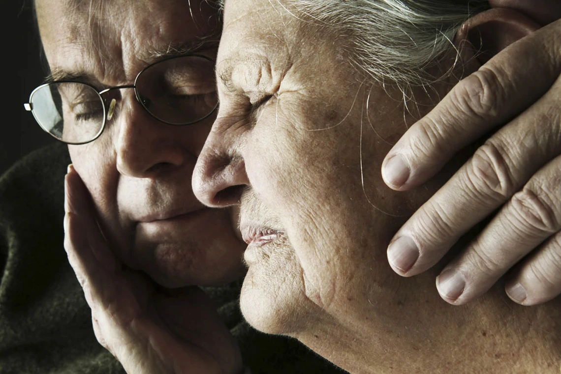 A middle-aged son comforting his aging mother.