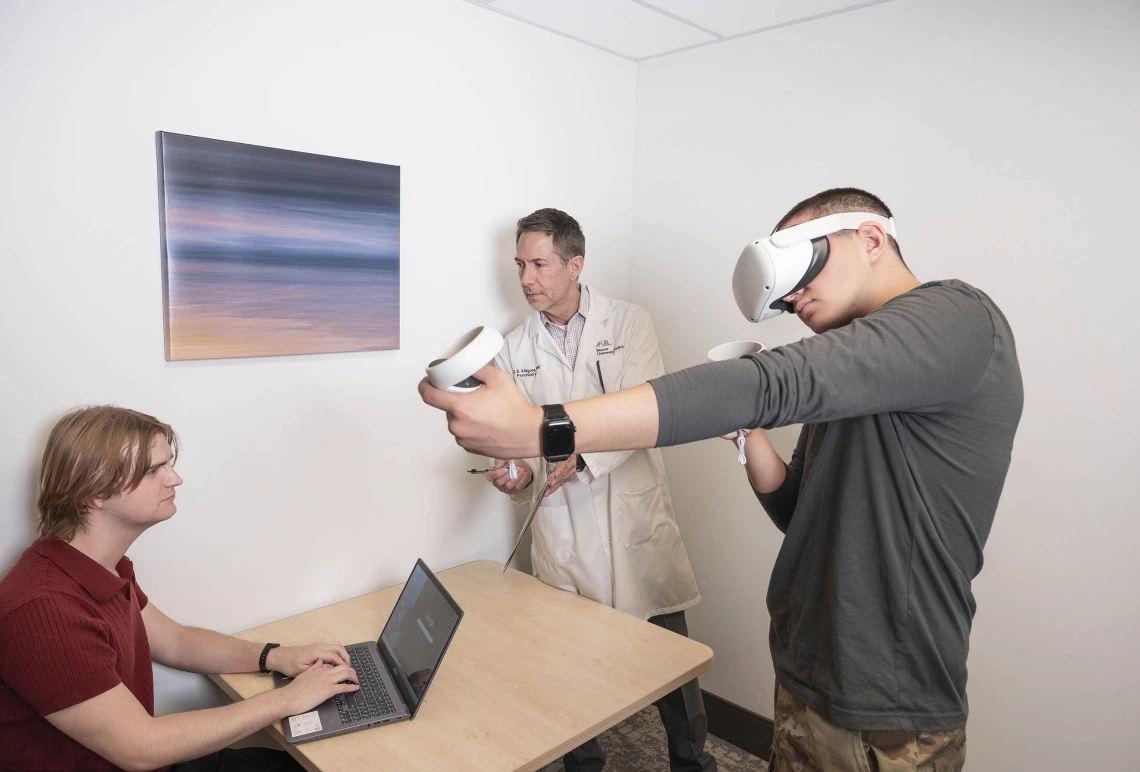 person using virtual reality headset and controllers while University of Arizona Health Sciences researchers observe in the background