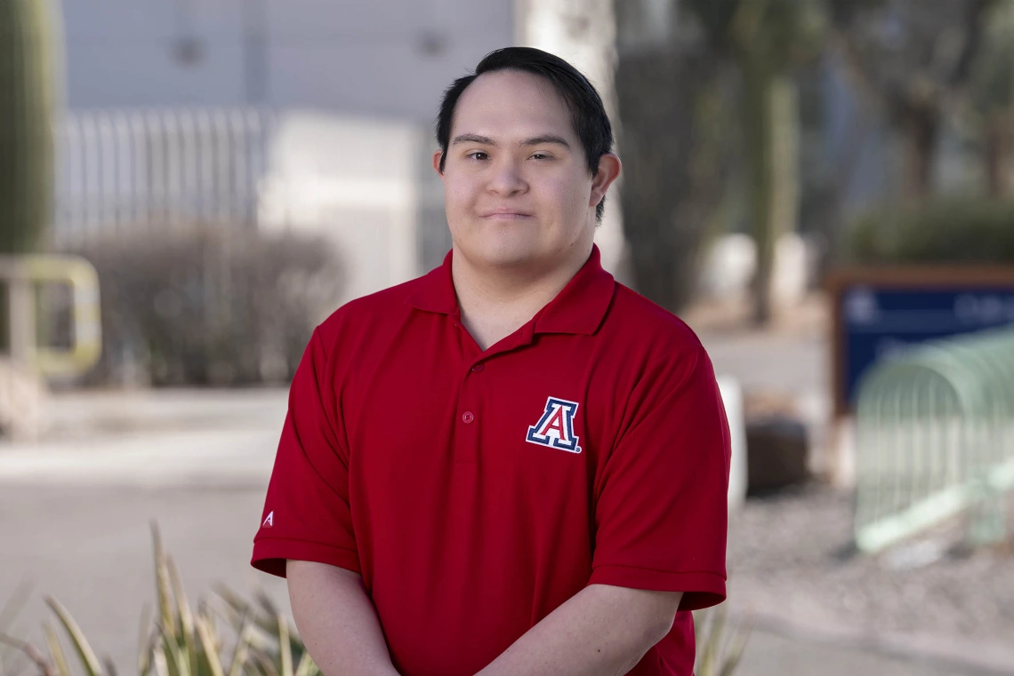 Portrait of Gabe Martinez wearing a University of Arizona logoed, red collared shirt.