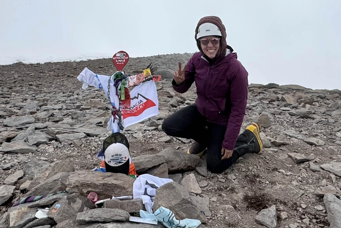 Nicola Baker crouches next to a memorial at the summit of Aconcagua, the tallest mountain in the Americas.