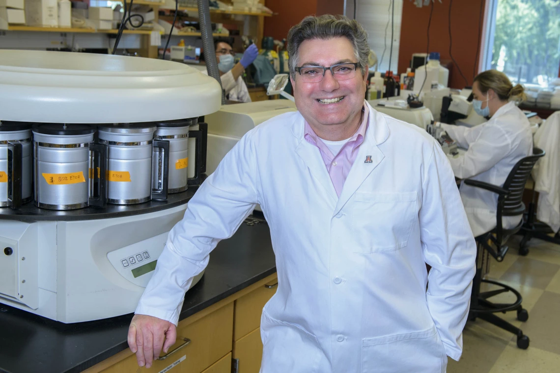 Researcher Klearchos Papas, PhD, poses in a lab dressed in a white lab coat.