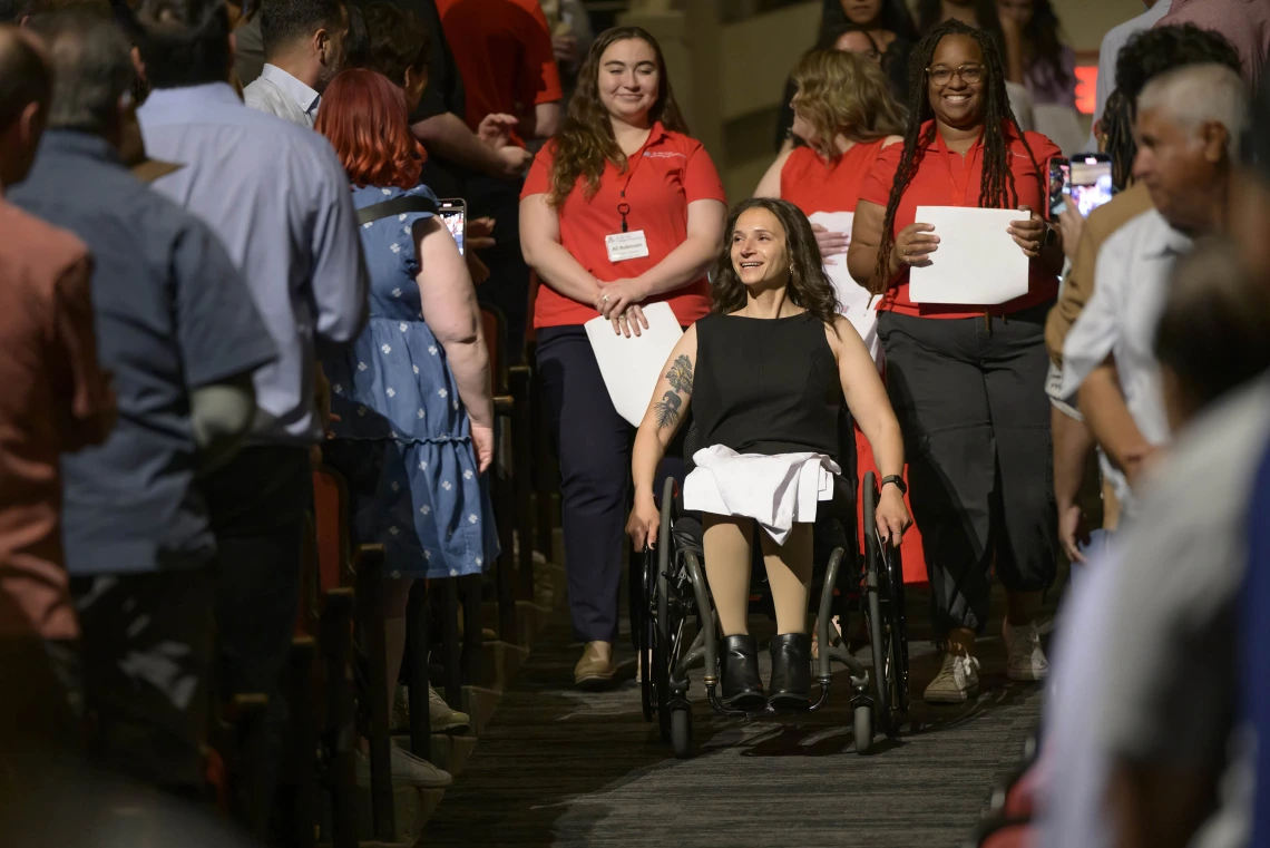 A pharmacy student in a wheelchair leads the class procession into Centennial Hall for their white coat ceremony.