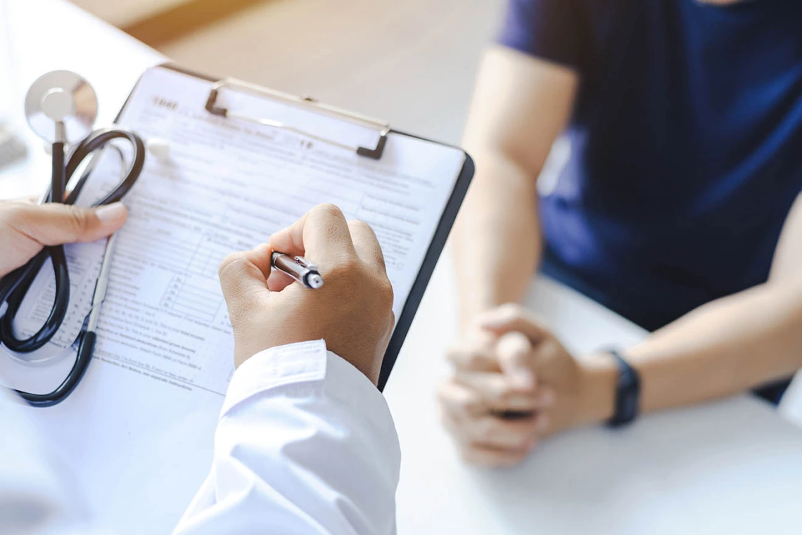  Doctor giving prescription to a patient and filling out medical form on a clipboard