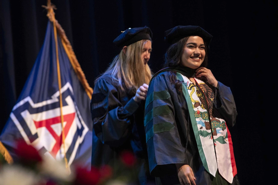 Medical student Jovanna Figueroa is hooded by University of Arizona College of Medicine – Phoenix professor Kathleen Brite Hillis during the graduation ceremony. Both are wearing graduation regalia. 