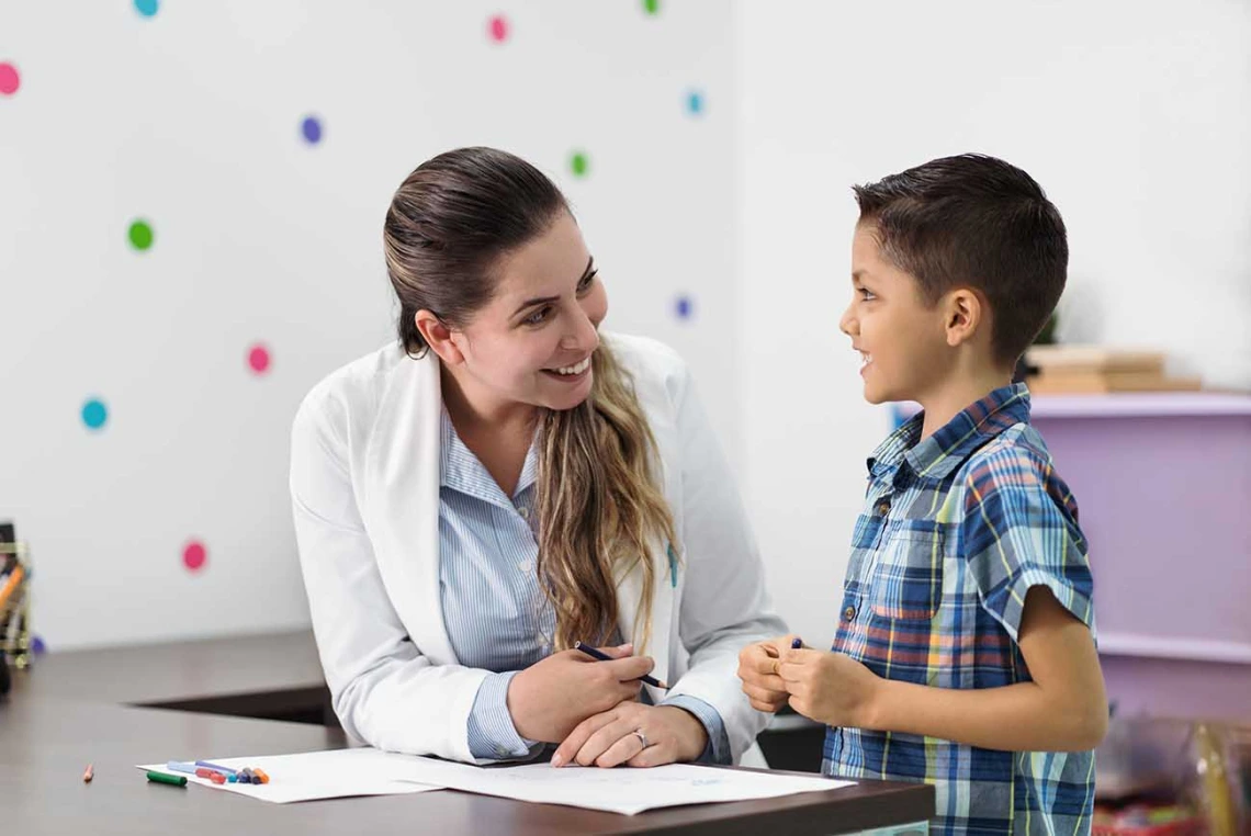 Happy psychologist and a litle boy smiling at each other