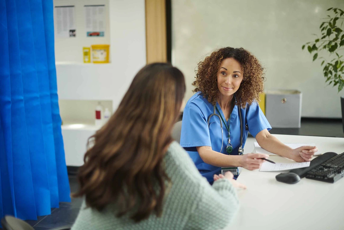 primary care physician smiles at patient while reviewing prescription details