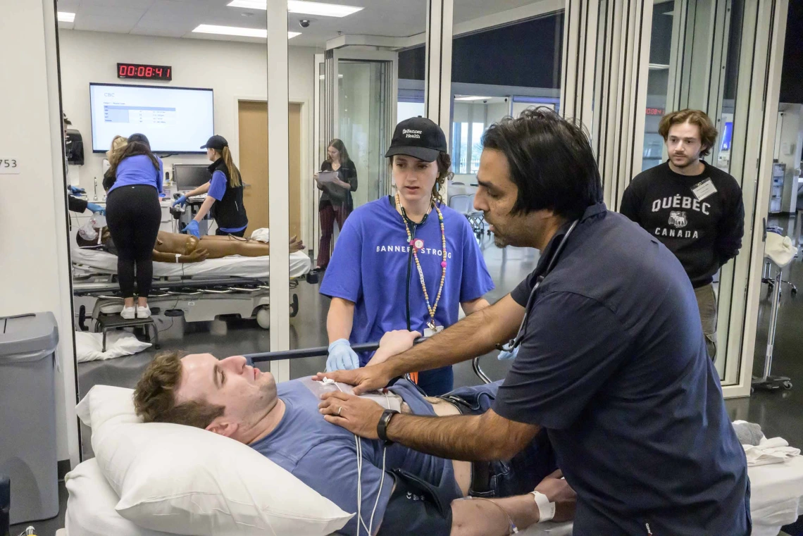 Several emergency room residents work on a volunteer patient in an ER-like setting as part of a medical simulation competition.