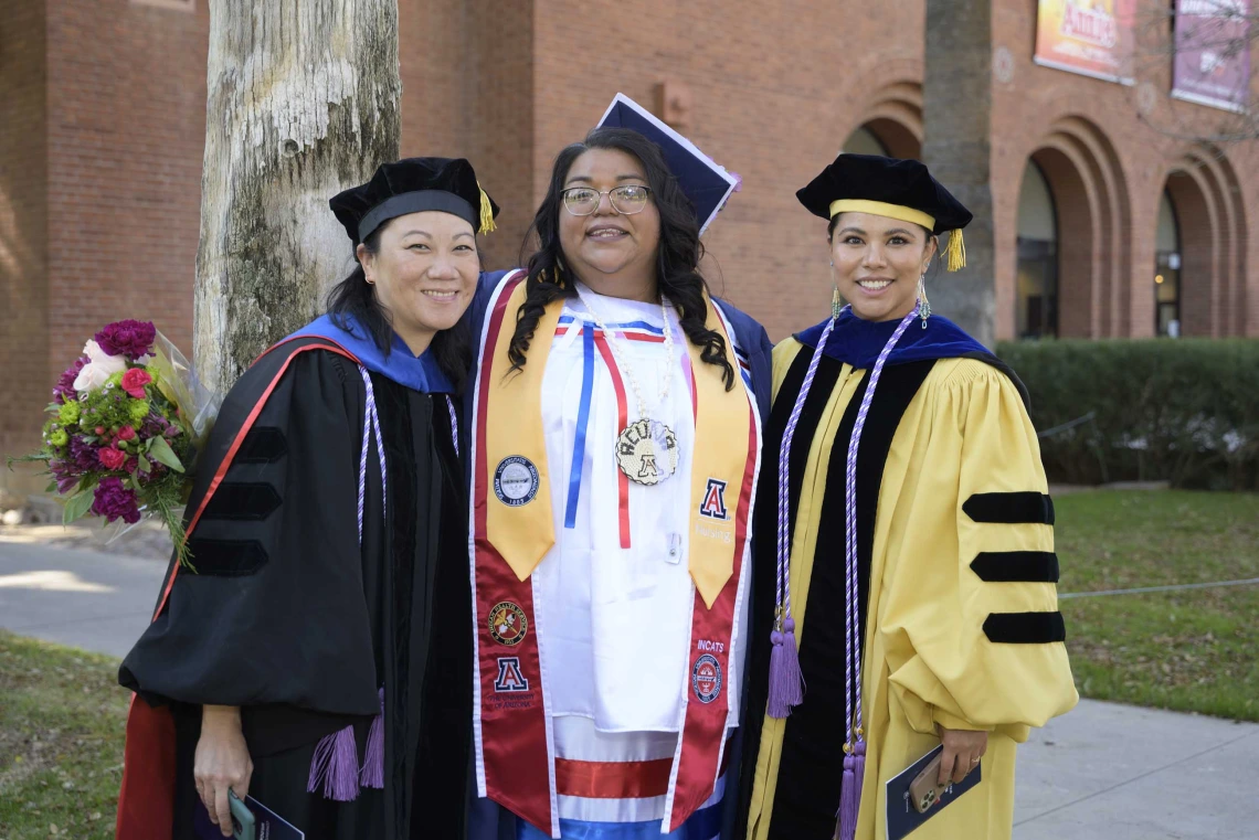 Two U of A College of Nursing faculty members pose with a graduating student after the college’s convocation ceremony.