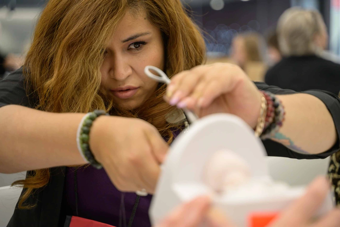 A nursing student focuses intently as she practices a medical procedure on a piece of simulation equipment. 