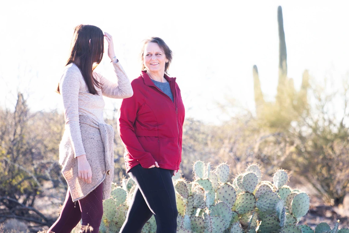 Lorre Laws, PhD, walks in the desert next to a young woman.