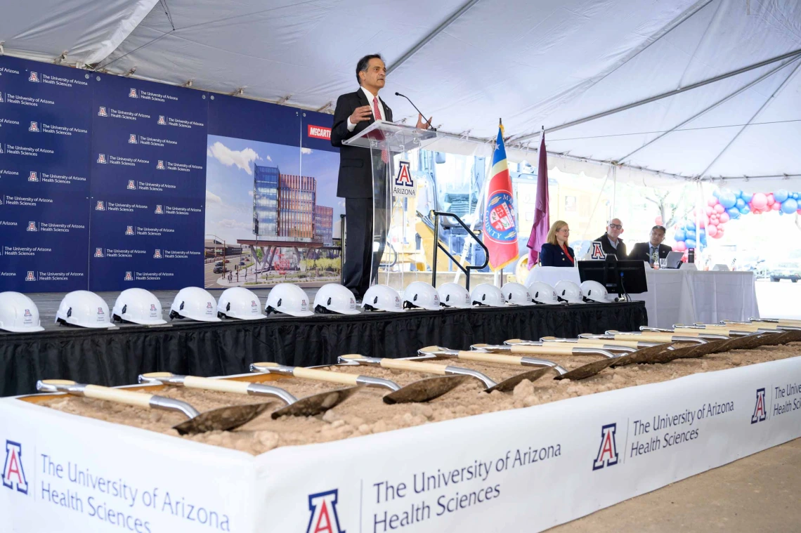 University of Arizona President Suresh Garimella stands on a stage with hard hats, shovels and dirt at his feet. 