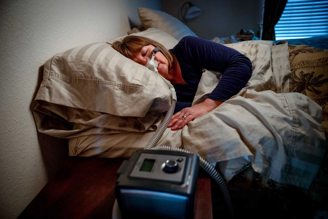 A woman in a bed using a CPAP machine