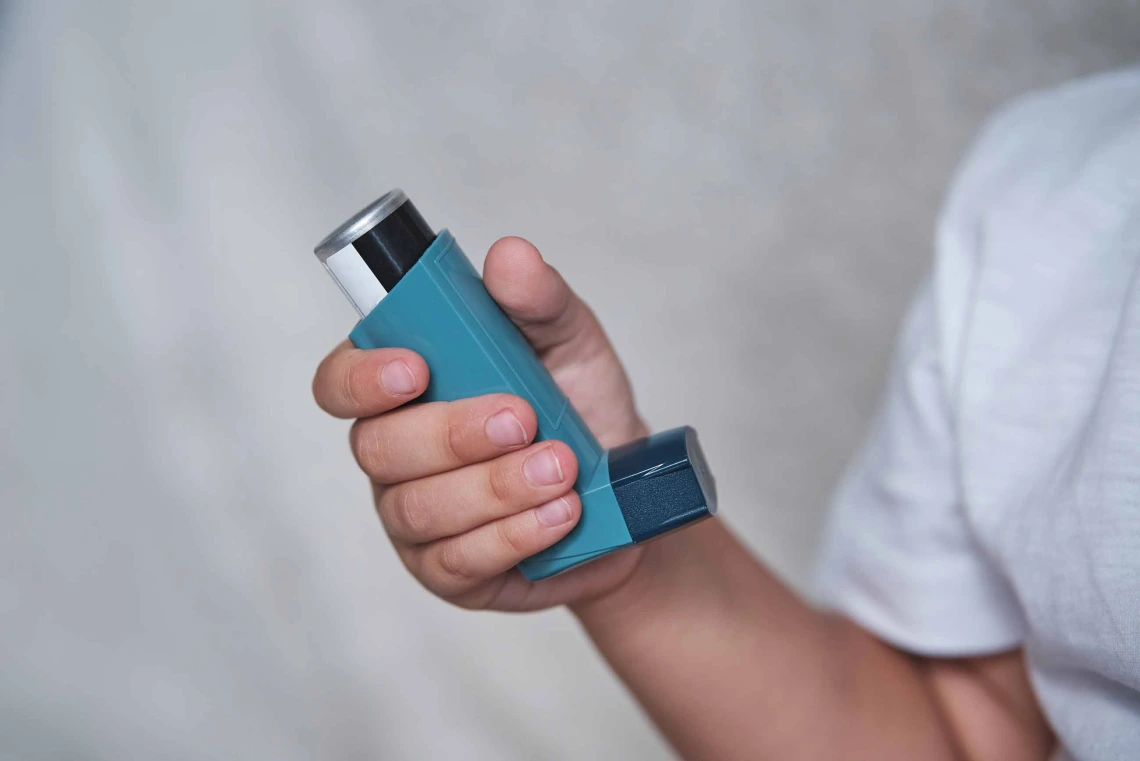 A person holds a blue asthma inhaler