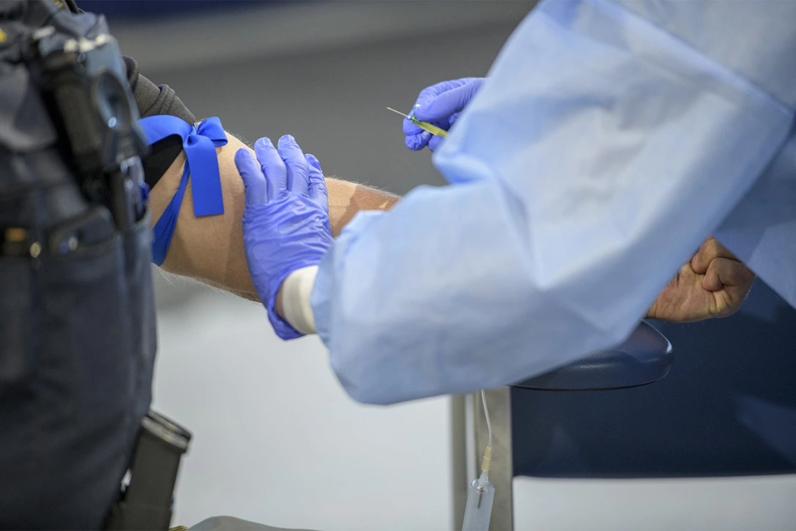 A police officer prepares for the antibody test, consisting of a blood draw.