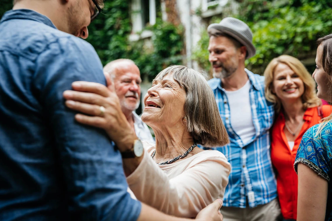 An elderly lady greeting some of her family members in a courtyard before a family meal.