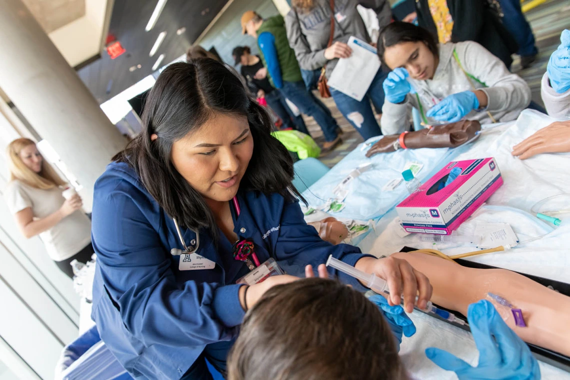 Students from the University of Arizona College of Nursing demonstrate administering an IV to a manikin..