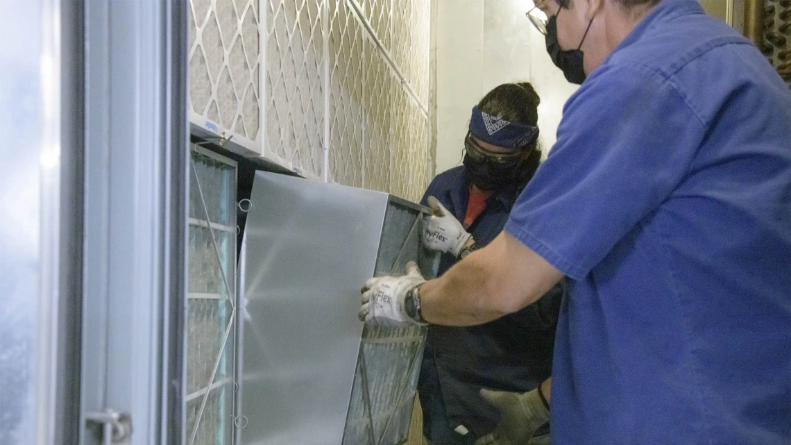 The University of Arizona Facilities Management team and key university stakeholders have worked diligently since spring 2020 to mitigate COVID-19 exposure for all students, staff and faculty. Pictured here, Facilities Management HVAC mechanics Sandra Acuna and Edward Leon install a new MERV 13 filter in the Health Sciences Innovation Building (HSIB).