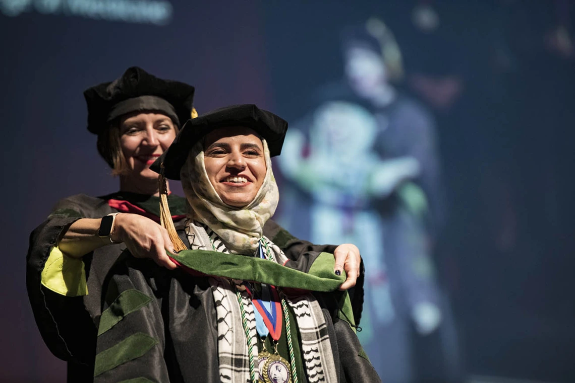 Associate Professor Mari Ricker, MD, hoods Tesneem Akram Tamimi during College of Medicine – Tucson class of 2022 convocation at Centennial Hall.