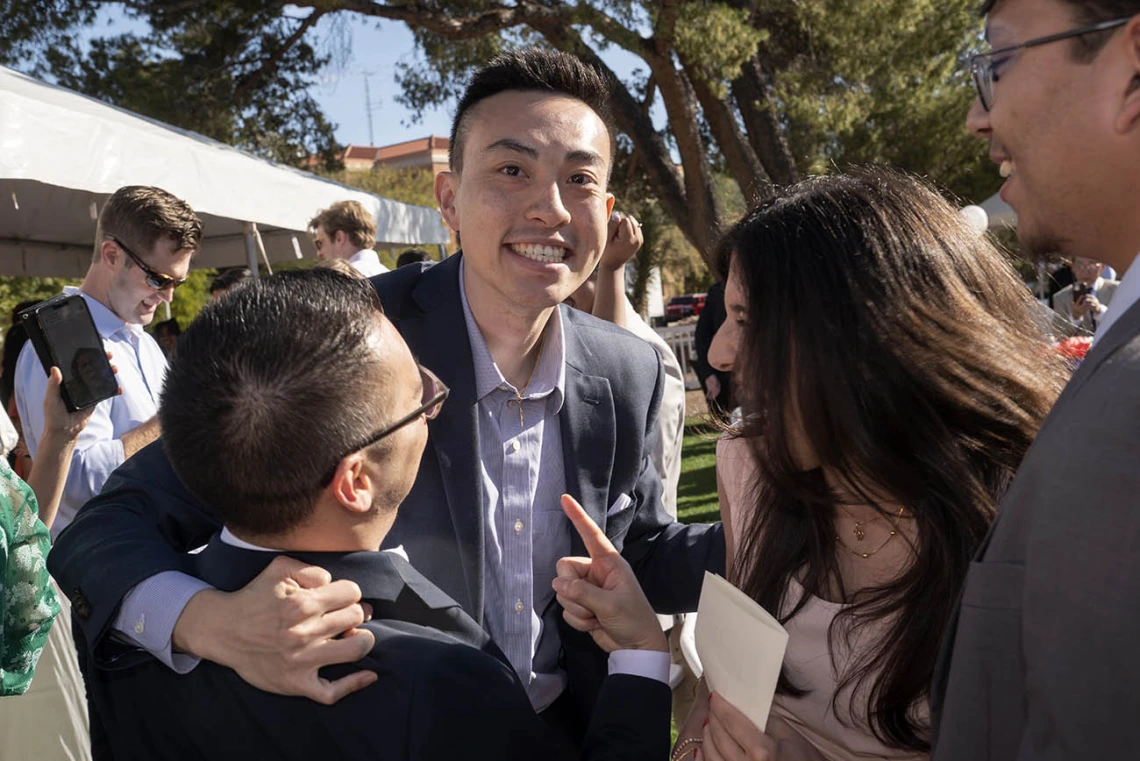 Young Asian man with big smile is hugged by friends. 